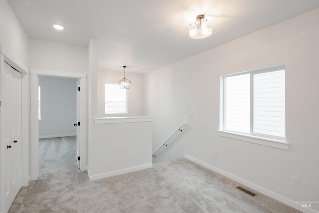 carpeted empty room featuring a chandelier