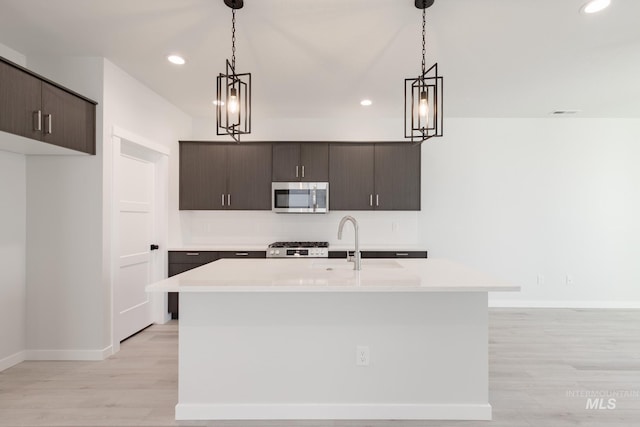 kitchen with tasteful backsplash, range, stainless steel microwave, light countertops, and light wood-type flooring