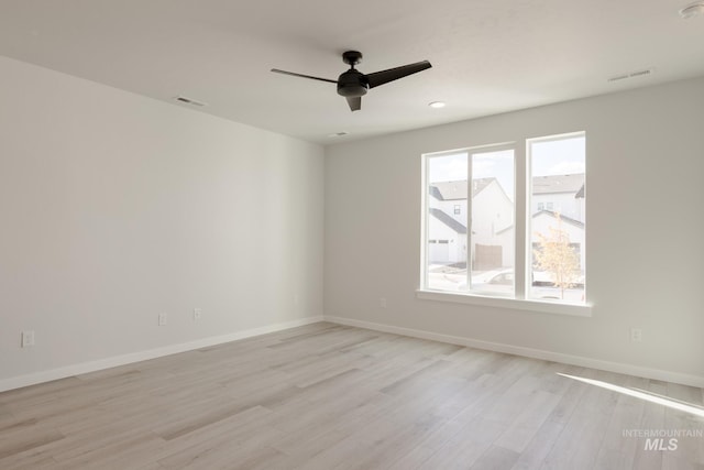 spare room featuring ceiling fan, light wood finished floors, visible vents, and baseboards