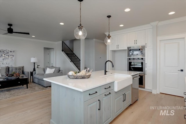 kitchen featuring sink, stainless steel appliances, an island with sink, light hardwood / wood-style floors, and white cabinets