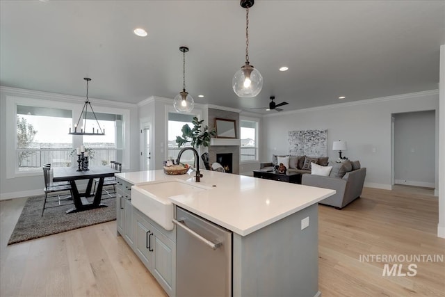 kitchen with dishwasher, a kitchen island with sink, sink, crown molding, and a fireplace