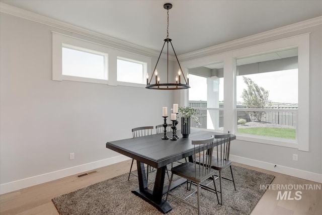 dining area featuring light wood-type flooring, a notable chandelier, and ornamental molding