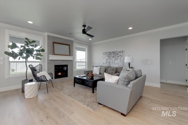 living room with ceiling fan, light wood-type flooring, a premium fireplace, and ornamental molding