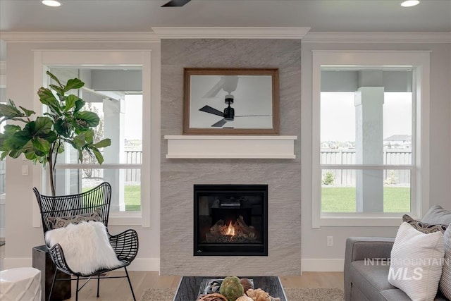 sitting room with a large fireplace, ceiling fan, light hardwood / wood-style floors, and ornamental molding