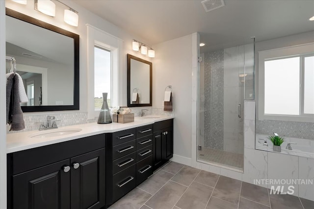 bathroom featuring plus walk in shower, vanity, a healthy amount of sunlight, and tile patterned flooring