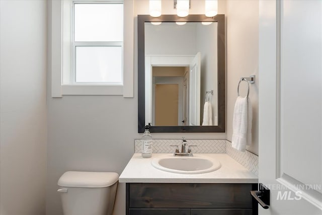 bathroom featuring vanity, toilet, and backsplash