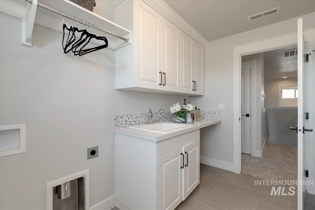 laundry room with electric dryer hookup, cabinets, sink, and light carpet