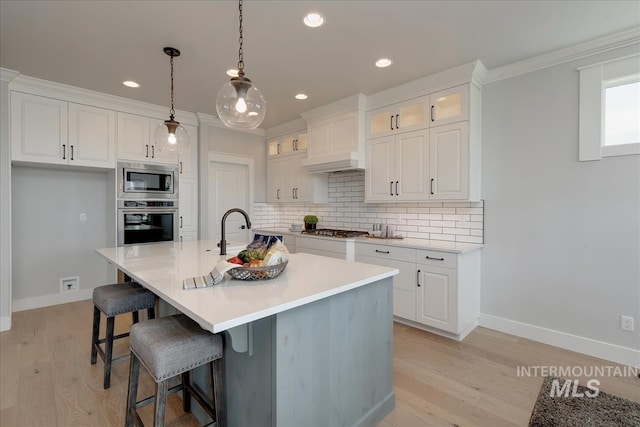 kitchen featuring backsplash, white cabinetry, an island with sink, and stainless steel appliances