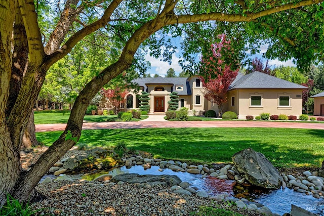 2634 W Sugarberry Dr, Eagle, ID 83616 - view of front of house featuring stucco siding, a front yard, a shingled roof, and a small pond
