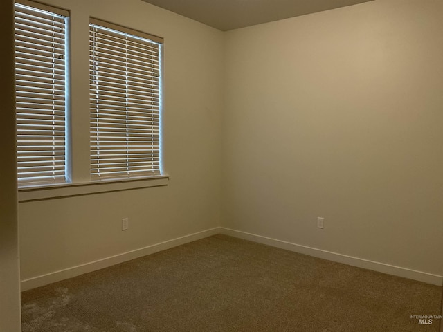 carpeted empty room featuring baseboards