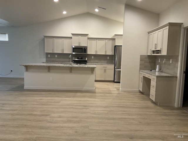 kitchen featuring light stone countertops, light wood finished floors, and stainless steel appliances