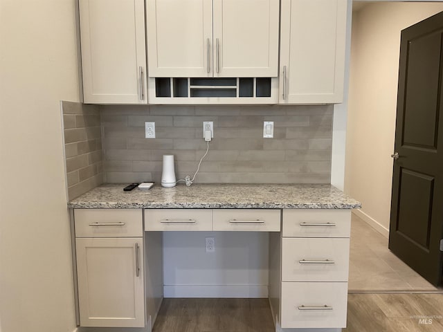 kitchen featuring light stone counters, wood finished floors, and open shelves