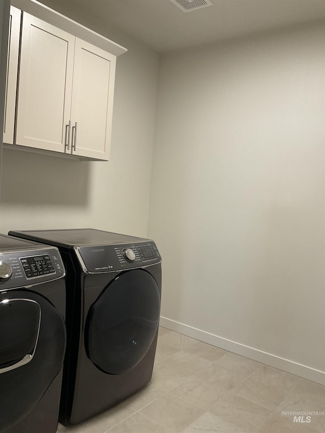 washroom featuring visible vents, cabinet space, baseboards, and washing machine and clothes dryer