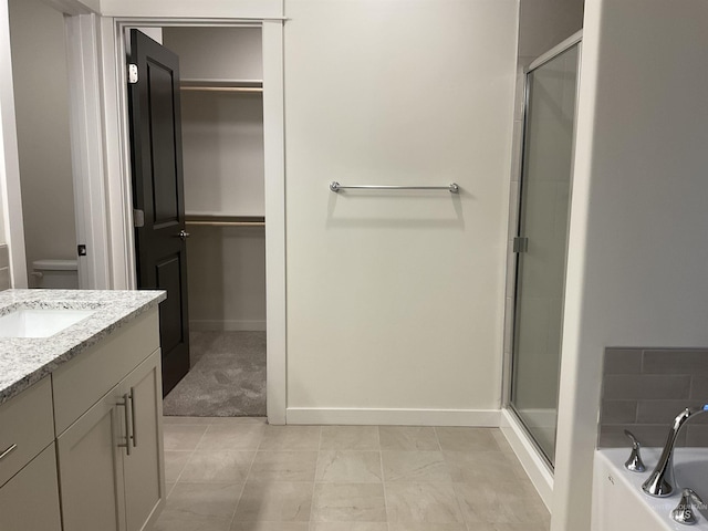 full bathroom featuring a bath, a shower stall, vanity, and a walk in closet