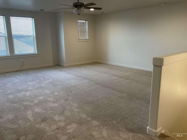 carpeted spare room featuring a ceiling fan and baseboards