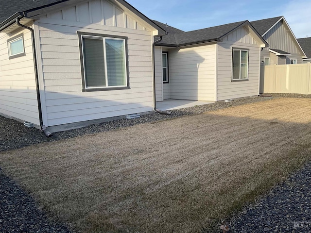 rear view of property with board and batten siding, a patio, and fence