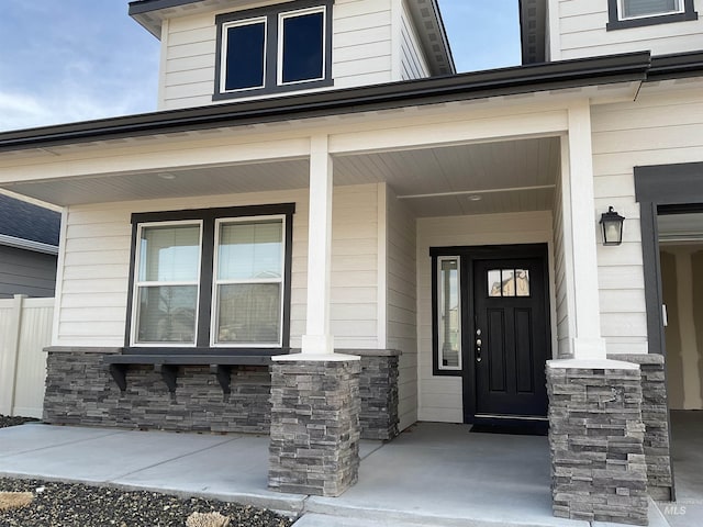 doorway to property with covered porch and stone siding