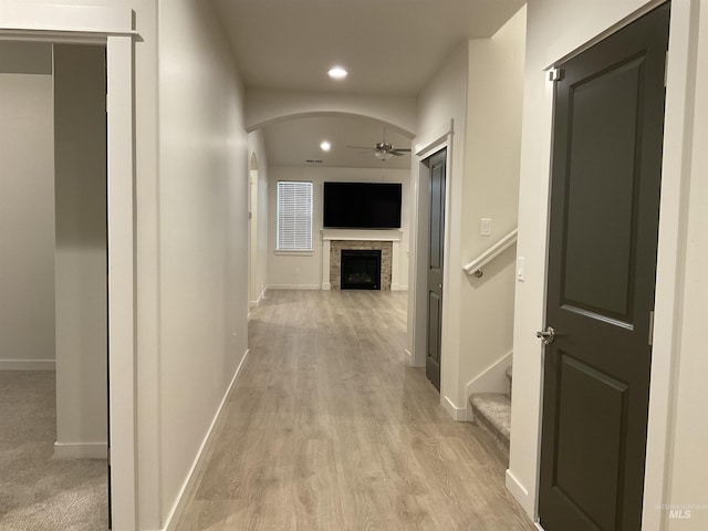 hallway featuring visible vents, baseboards, light wood finished floors, recessed lighting, and arched walkways