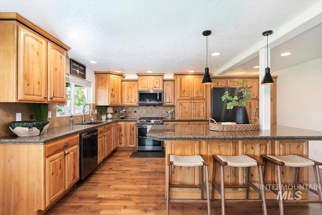 511 Keogh Ln, Caldwell, ID 83607 - kitchen with stainless steel appliances, a sink, a breakfast bar area, light wood finished floors, and recessed lighting