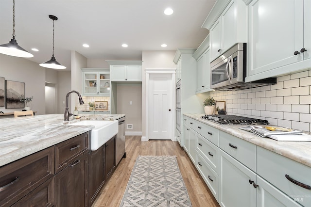 5404 S Palatino Ave, Meridian, ID 83642 - kitchen with appliances with stainless steel finishes, white cabinetry, light wood finished floors, dark brown cabinetry, and decorative backsplash