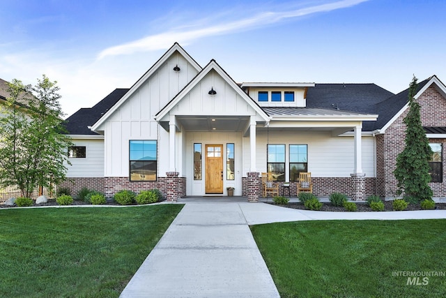 view of front of house with a porch, brick siding, board and batten siding, and a front lawn