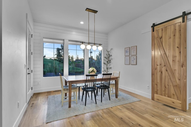 dining area featuring a barn door, light wood finished floors, baseboards, and recessed lighting