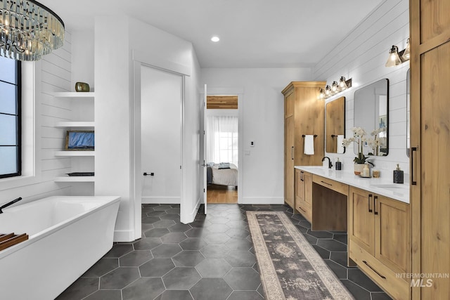 full bath with ensuite bath, a freestanding bath, double vanity, recessed lighting, and tile patterned floors