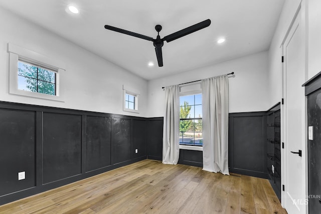 empty room featuring ceiling fan, a decorative wall, a wainscoted wall, hardwood / wood-style flooring, and recessed lighting