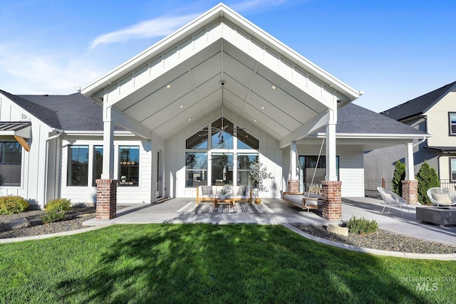 rear view of property featuring a patio area, a yard, an outdoor hangout area, and roof with shingles