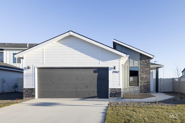 view of front of house featuring an attached garage, stone siding, board and batten siding, and concrete driveway