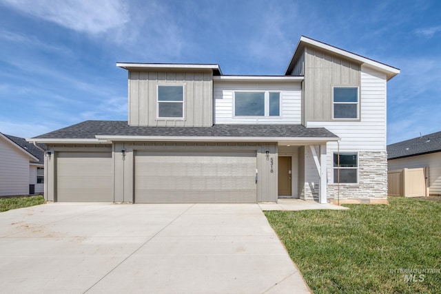 view of front of home featuring a front lawn, concrete driveway, fence, a garage, and board and batten siding