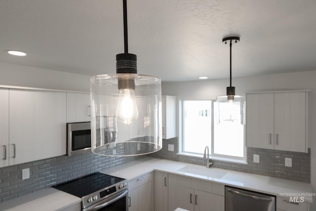 kitchen featuring light countertops, backsplash, stainless steel appliances, and a sink