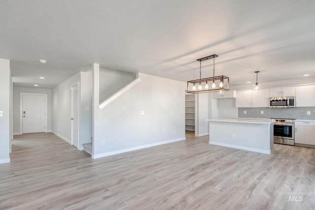 kitchen featuring white cabinets, open floor plan, tasteful backsplash, and stainless steel appliances