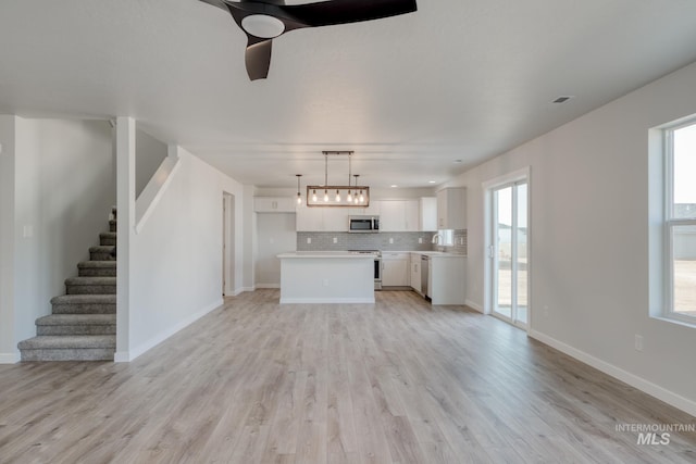 unfurnished living room with a ceiling fan, a healthy amount of sunlight, and light wood-type flooring