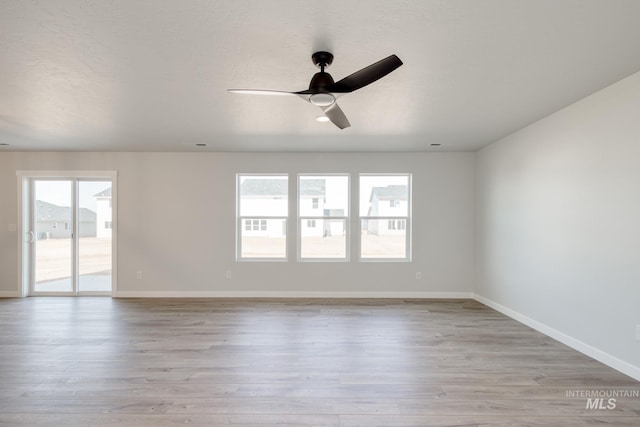 unfurnished room with wood finished floors, a ceiling fan, and baseboards