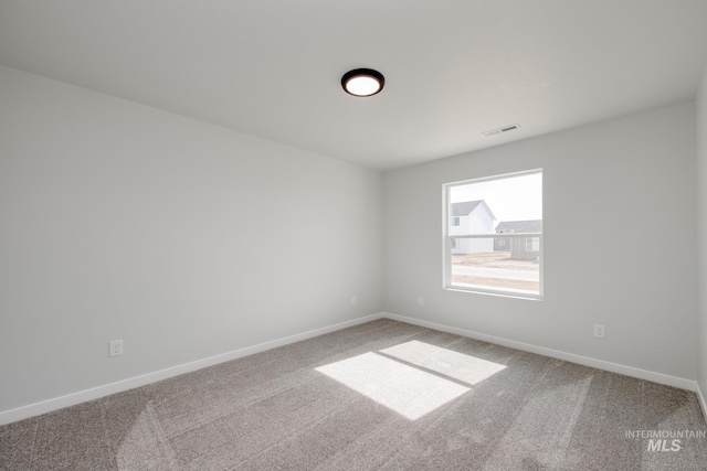 carpeted spare room featuring visible vents and baseboards
