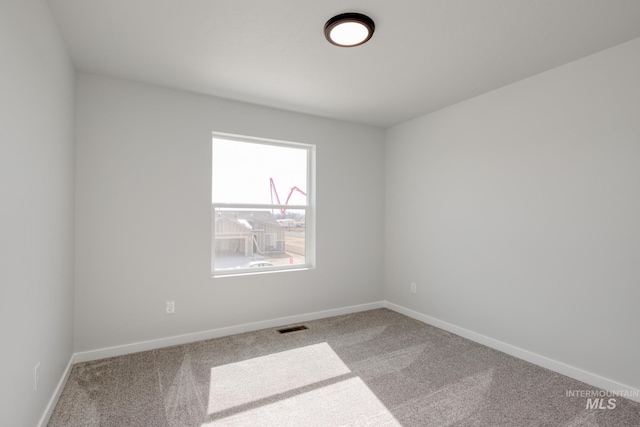 carpeted empty room featuring baseboards and visible vents