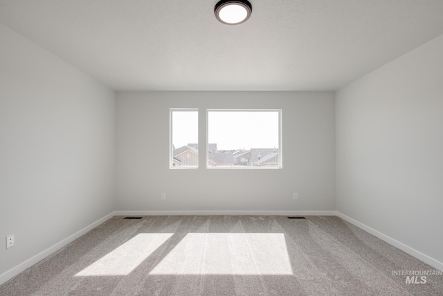 empty room featuring visible vents, baseboards, and carpet floors