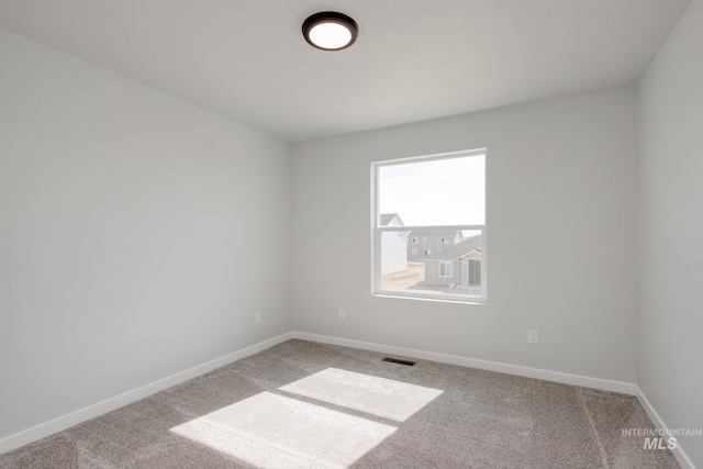 carpeted empty room featuring baseboards and visible vents