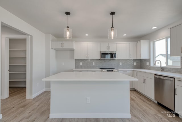 kitchen with white cabinets, stainless steel appliances, a sink, and a kitchen island
