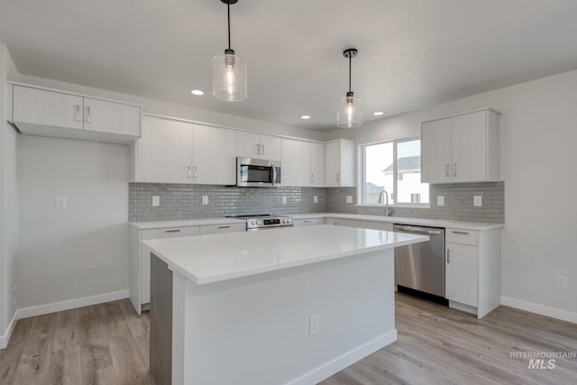 kitchen featuring white cabinets, tasteful backsplash, light wood-style flooring, and stainless steel appliances