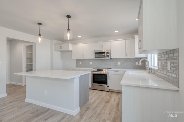 kitchen with appliances with stainless steel finishes, tasteful backsplash, a sink, and light wood-type flooring