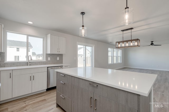 kitchen with ceiling fan, stainless steel dishwasher, a sink, and light wood-style floors
