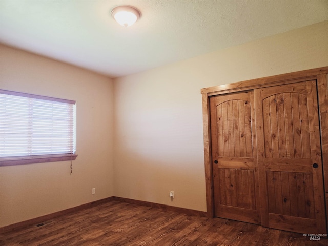 unfurnished bedroom with dark wood-type flooring