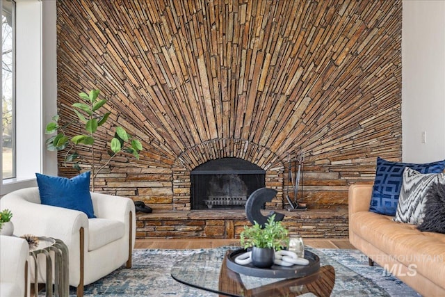 living area featuring a stone fireplace and wood finished floors