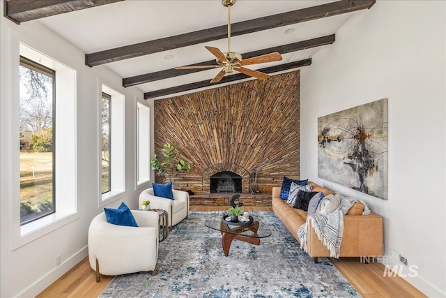 living area with wood finished floors, a healthy amount of sunlight, and a fireplace with raised hearth