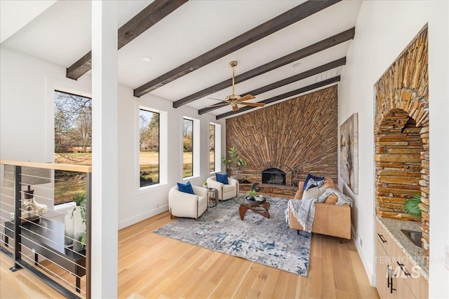 living room with beamed ceiling, a fireplace, baseboards, and wood finished floors