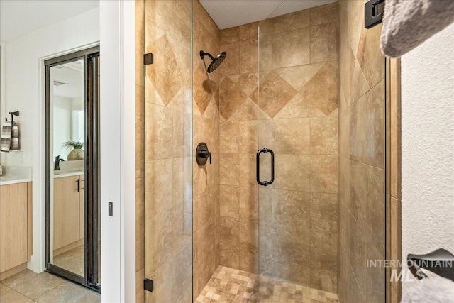 full bath featuring tile patterned floors, a stall shower, and vanity