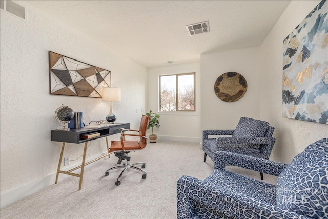 carpeted home office with a textured wall, visible vents, and baseboards