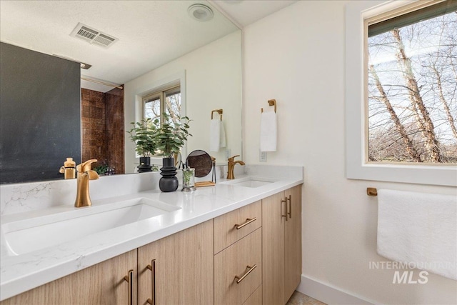 full bathroom with double vanity, visible vents, and a sink